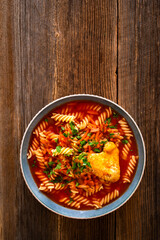 Tomato soup with chicken thigh and noodles on wooden table