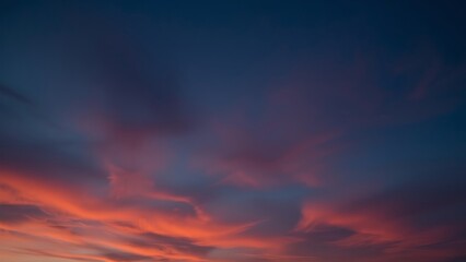 Magnificent sky at sunset painted in vibrant hues of orange, pink, and purple, with soft clouds drifting across the glowing horizon, creating a serene and breathtaking view of nature’s evening beauty