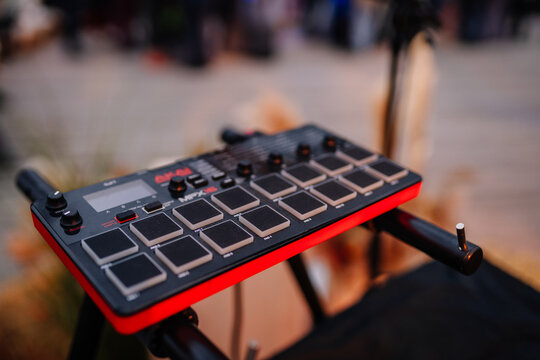 Close-up of an Akai MPX16 electronic drum pad sampler on a stand, used for live music performance or sound production, with soft evening light.