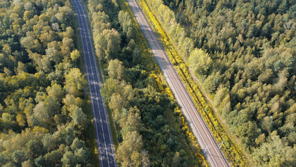 Aerial view of railway and highway cutting through lush forest landscape