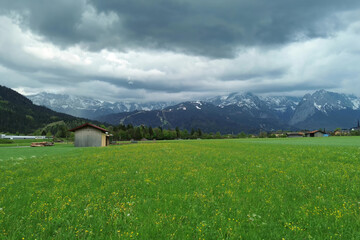 Alpine valley with wooden barns and cloudy sky