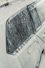 Here is a detailed closeup photography of a car that is completely covered in rich, thick soap as...