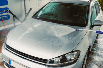 A Clean Start A shiny silver car is being meticulously washed at a selfservice car wash station,...