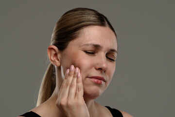 Fototapeta premium Woman Experiencing Toothache and Holding Cheek in Pain