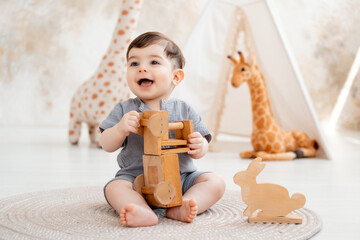 a smiling baby plays in a children's room with soft toys and a teepee, and a cute baby in a gray...