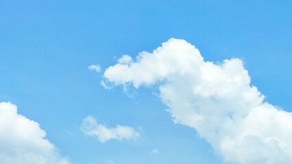 Bright blue sky with fluffy white cumulus clouds, indicating a clear and bright day. Nature...