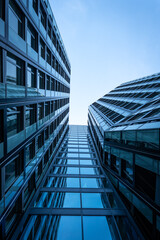 Upward View Along a High-Rise Facade Reflecting the Blue Sky, Creating an Abstract Composition of Angles and Geometry in Glass and Steel