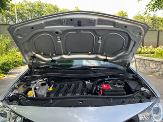 This is a closeup view of a car engine that has its hood open, allowing us to observe the...