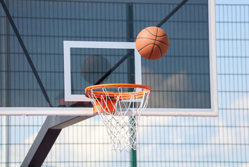 A basketball is in the air above a basketball hoop