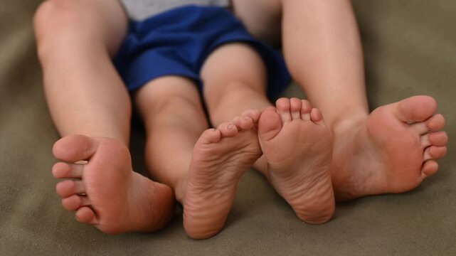 mother son 5 years old fooling around playing relaxing in a hammock outdoors in a pine forest at a campsite. Tourism, active recreation, time spent with children legs foot closeup no face