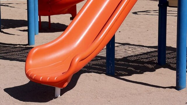 orange plastic playground slide set over sandy terrain with blue support poles at Falcon Field Park