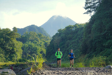Asian Indonesian couple trail running near Merapi volcano, active sport and sustainable lifestyle