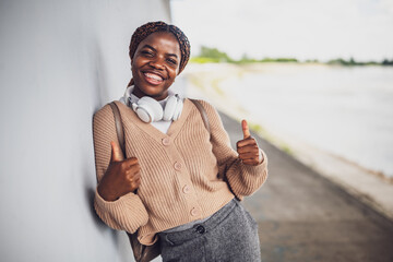 Portrait of young happy black woman with dental braces. She is looking at camera and showing thumbs up.