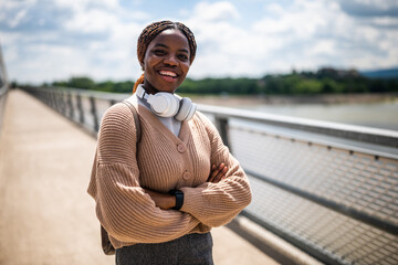 Happy young black woman is looking at camera and smiling. She is enjoying sunny day outdoor.