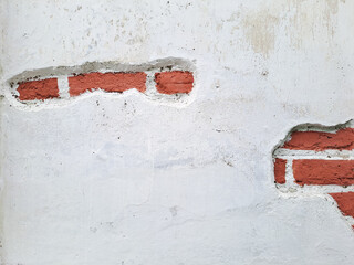 Texture of an old brick wall with damaged plaster and cracked white paint.	
