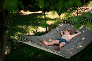 Child sleeping soundly in hammock on warm summer afternoon