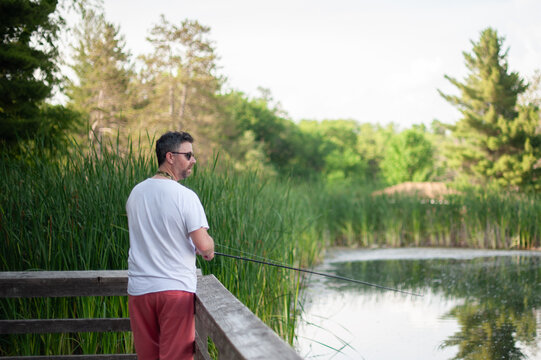 Man stands quietly fishing alone on peaceful summer dock