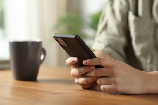 Woman hands texting on mobile phone on wooden table - Powered by Adobe