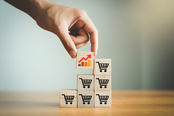 Business Development and Sales Increase Concept. Hand Adding Cube with Shopping Cart and Growth Graph.