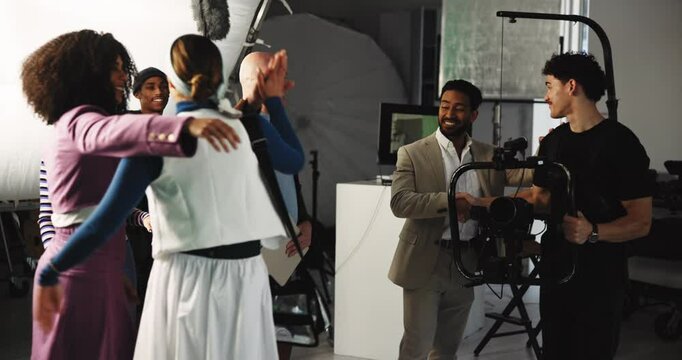 Happy people, director or production team with high five in celebration for filmmaking on set. Excited group, actor or cast with videographer or camera for success or video commercial in studio