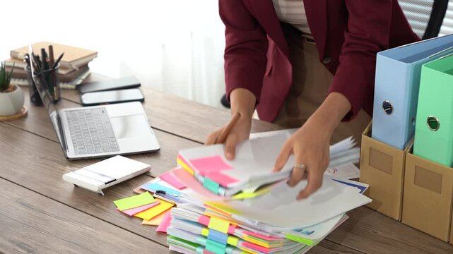 Organizing Paperwork: An professional is carefully arranging documents on a clean office desk, promoting an image of efficiency and focus within the workplace.
