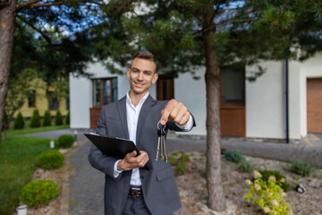 Real estate agent holding keys and clipboard in front of modern house for property