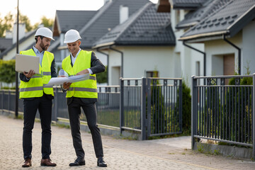 Construction workers reviewing plans in residential area