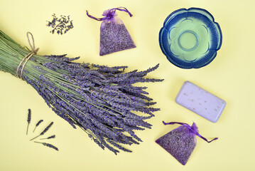 Bouquet of lavender flowers and lavender products on the yellow background. Top view.