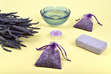 Bouquet of lavender flowers and lavender products on the yellow background. Selective focus.