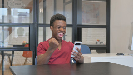 Dissatisfied Casual African Man Using Phone at Workplace