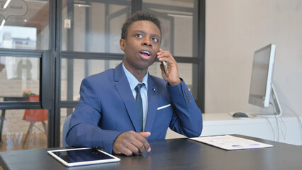 Young African Businessman Talking on phone at Workplace