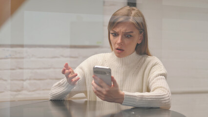 Young Woman with Trading Loss on Phone at Workspace