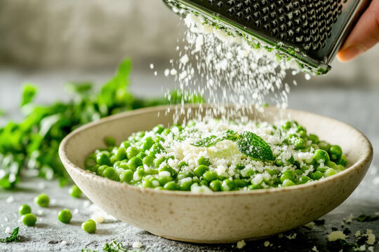 Grated Cheese Over Peas. Fresh peas are grated with cheese in a bowl with mint on top. - Powered by Adobe