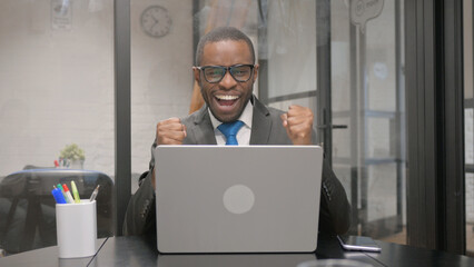 African Businessman Celebrating Success on Laptop