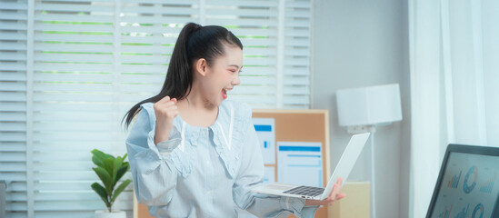 Confident beauty Asian office woman in a formal blouse hard working at her desk, reviewing a...