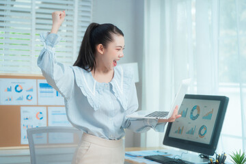 Confident beauty Asian office woman in a formal blouse hard working at her desk, reviewing a...