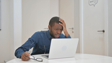 Young African Man with Loss on Laptop