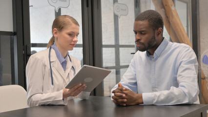 Fototapeta premium Middle Aged Doctor Discussing Treatment Plan with Patient on Digital Tablet