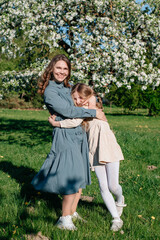 Naklejka premium A mother hugs her child on the street. A woman and a teenage girl in a summer park. A happy family, mother and daughter.