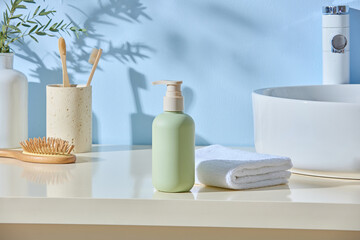 Ceramic bottles, toothbrushes and sponge arranged with folded towel in soft blue light. Japandi...
