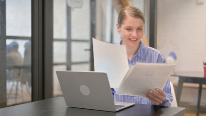 Woman Celebrating Profits while Reading Annual Business Report