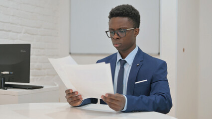 Young African Businessman Reading Documents in Office