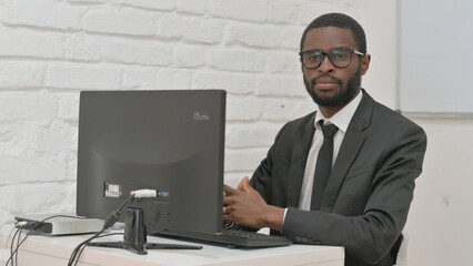 Confident Businessman Looking at Camera While Working on Computer