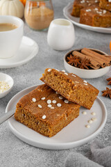 Pumpkin brown butter blondies or pumpkin cake with white chocolate drops and spices on a gray concrete background. Dessert for Thanksgiving or Halloween.