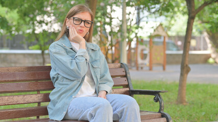 Obraz premium Uncomfortable Young Woman with Toothache on a Park Bench