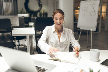 Female professional reviewing documents on laptop in office environment