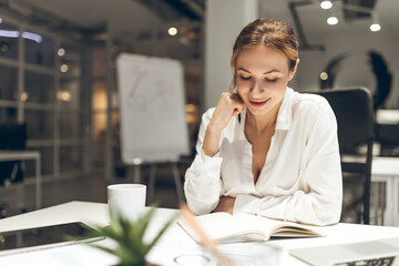 Female professional reviewing documents on laptop in office environment