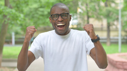Excited Young African Man with Fists Pumped Outdoors