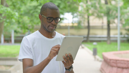 Young African Man Using a Tablet in a Park