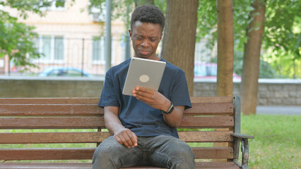 Fototapeta premium Casual African Man Expressing Disbelief While Using a Tablet
